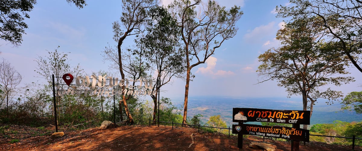 A dirt path leading to a viewpoint with a sign indicating 'Chom Ta Wan Cliff' and 'Phi Wuang National Park' in both English and Thai.