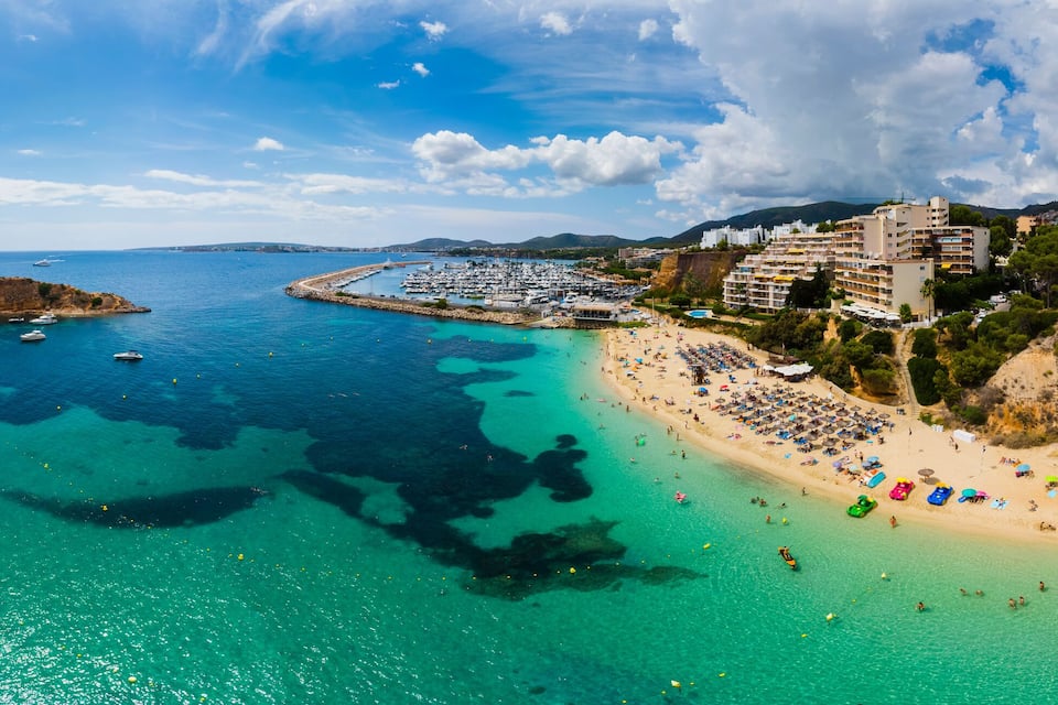 Une ville côtière avec une plage, des bateaux et une petite île.