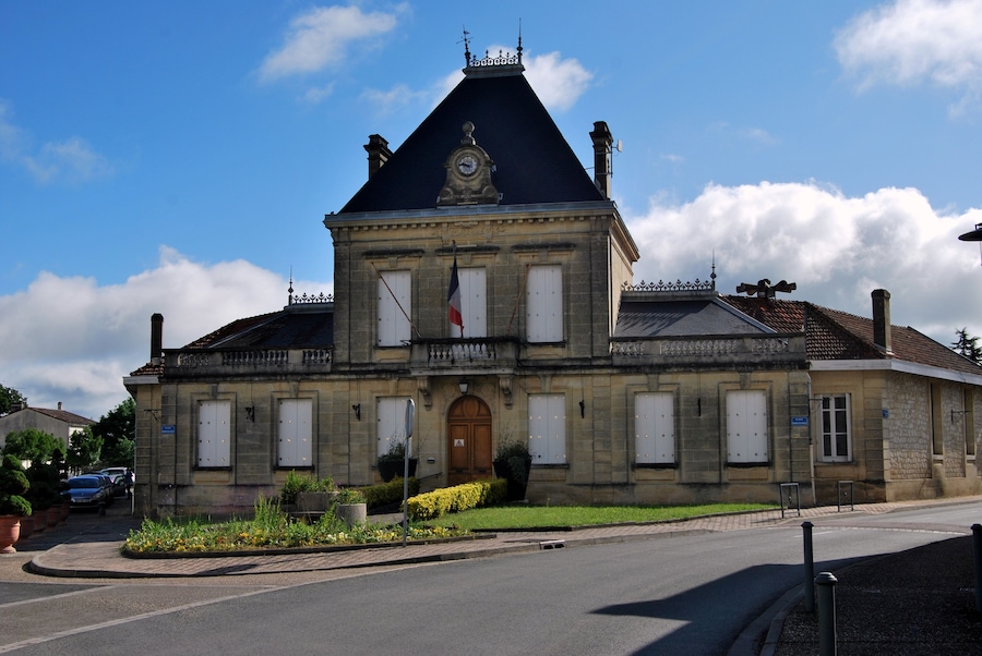 Un bâtiment historique doté d’un clocher, d’un drapeau et d’un jardin bien entretenu.