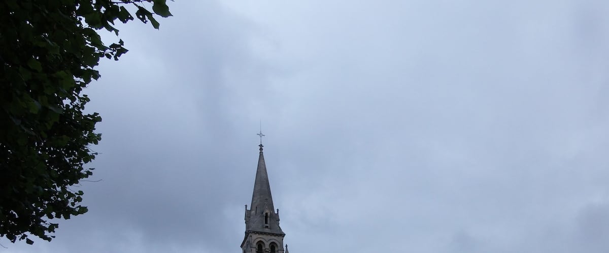 A historic church with a tall spire and a rounded section.