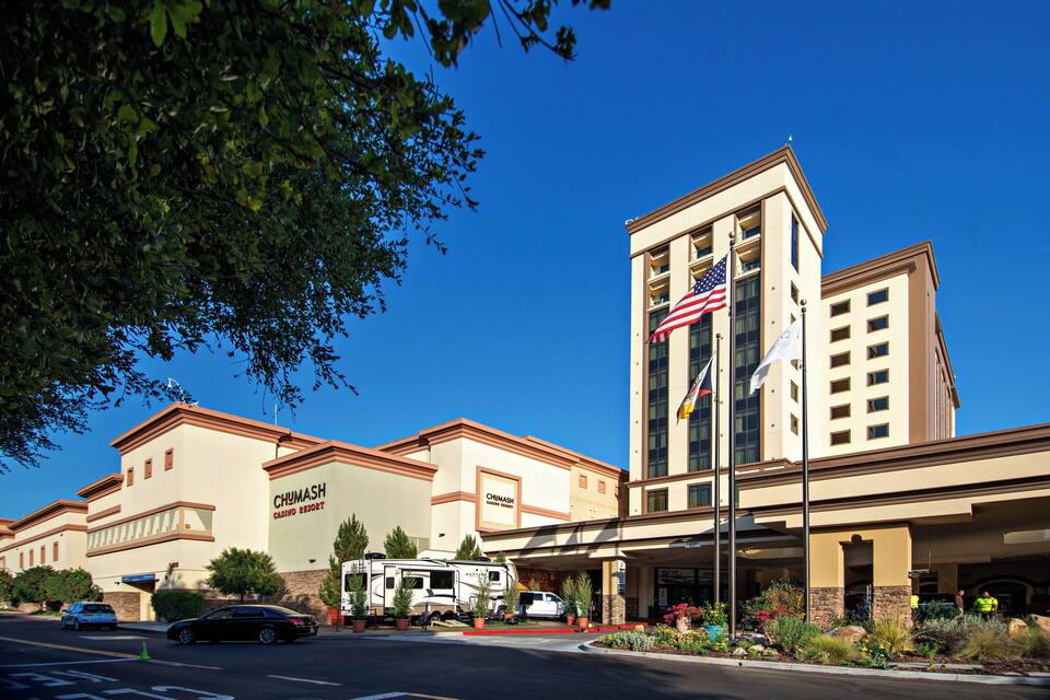 Et hotel med et amerikansk flag, et skilt der siger "Chumash Casino Resort", og en parkeringsplads med biler og autocampere.