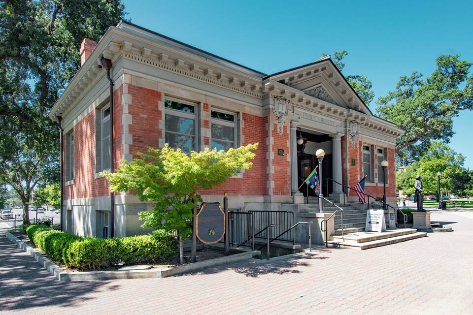 A historic brick building with a grand entrance, steps, and a flagpole.