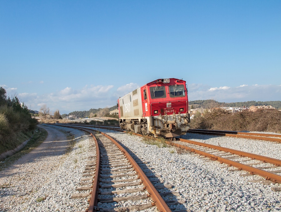 A red train on a railway track curving to the right.