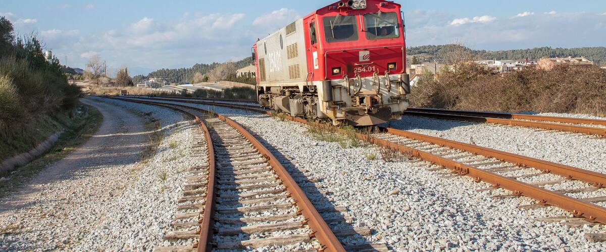 A red train on a railway track curving to the right.