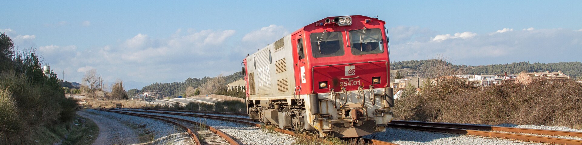 A red train on a railway track curving to the right.