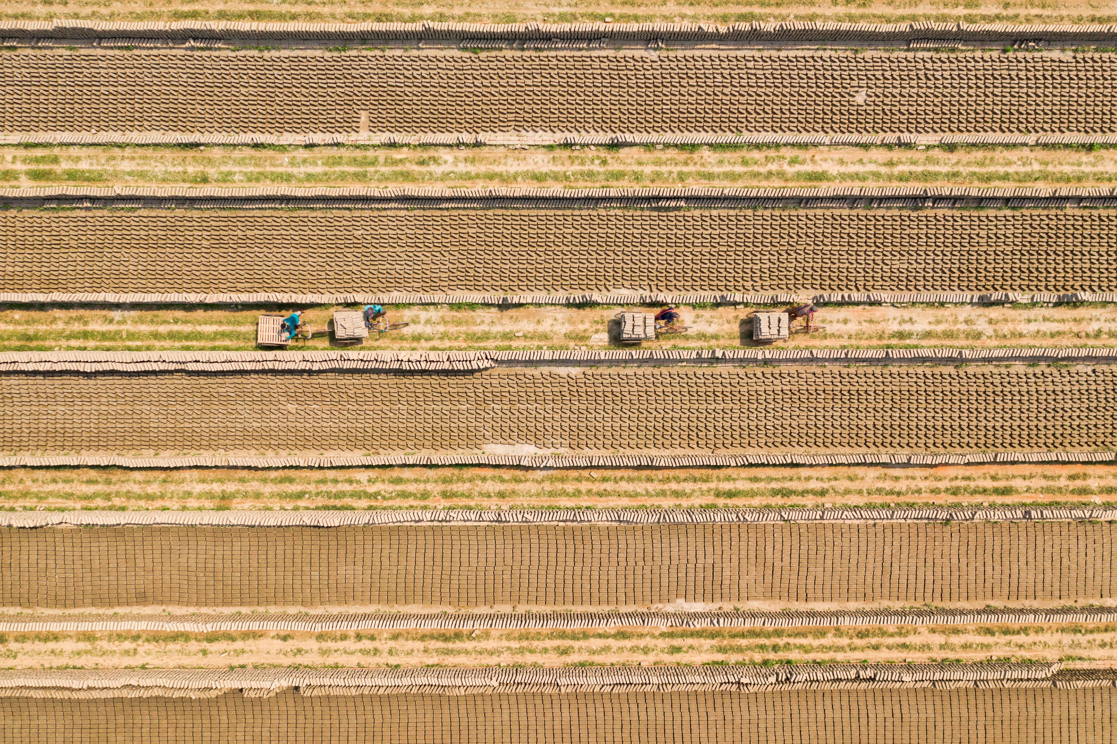 Aerial view of a brick factory from above, people working arranging the bricks near Keraniganj township, Dhaka province, Bangladesh.