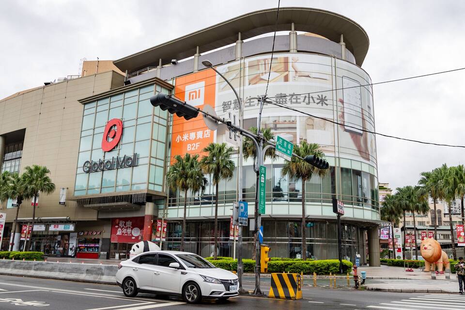 Un centre commercial moderne, reconnaissable à son grand panneau « Global Mall », à ses palmiers et à une imposante statue de lion.