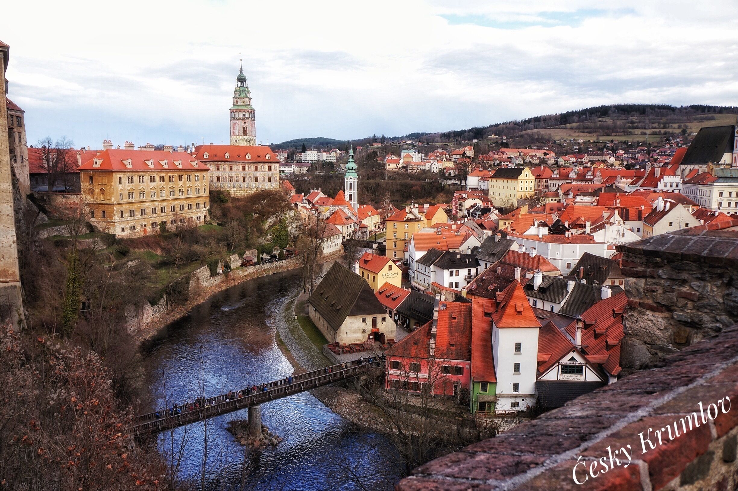 A historic town with a river, a prominent tower, and a bridge.