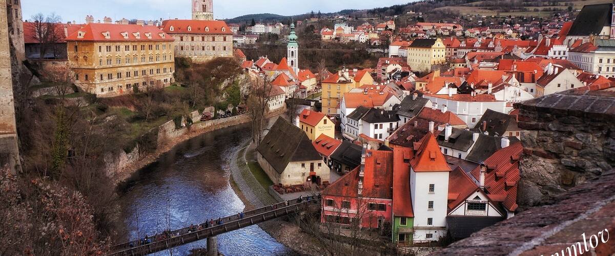 A historic town with a river, a prominent tower, and a bridge.