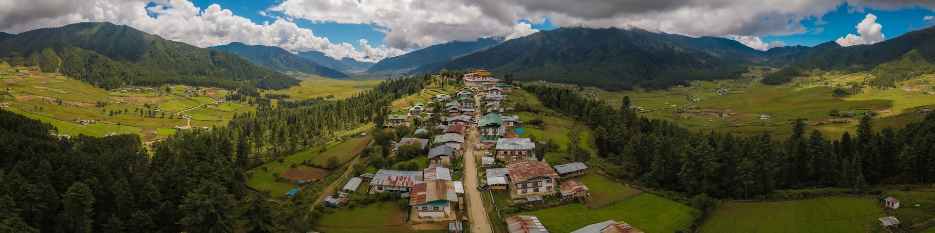 Aerial view of Gangtey Monastery atop a hill overlooking the lush Phobjikha Valley under a sky of dramatic clouds, Gangtey village, Wangdue Phodrang, Bhutan.