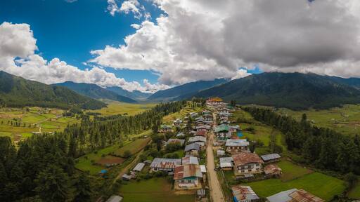 Aerial view of Gangtey Monastery atop a hill overlooking the lush Phobjikha Valley under a sky of dramatic clouds, Gangtey village, Wangdue Phodrang, Bhutan.
