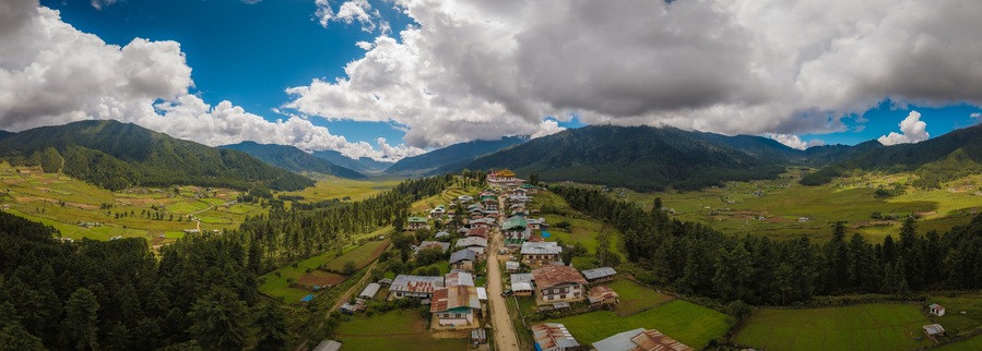 Aerial view of Gangtey Monastery atop a hill overlooking the lush Phobjikha Valley under a sky of dramatic clouds, Gangtey village, Wangdue Phodrang, Bhutan.