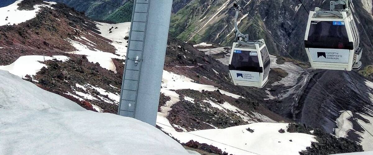 A cable car system with snowy mountains in the background.