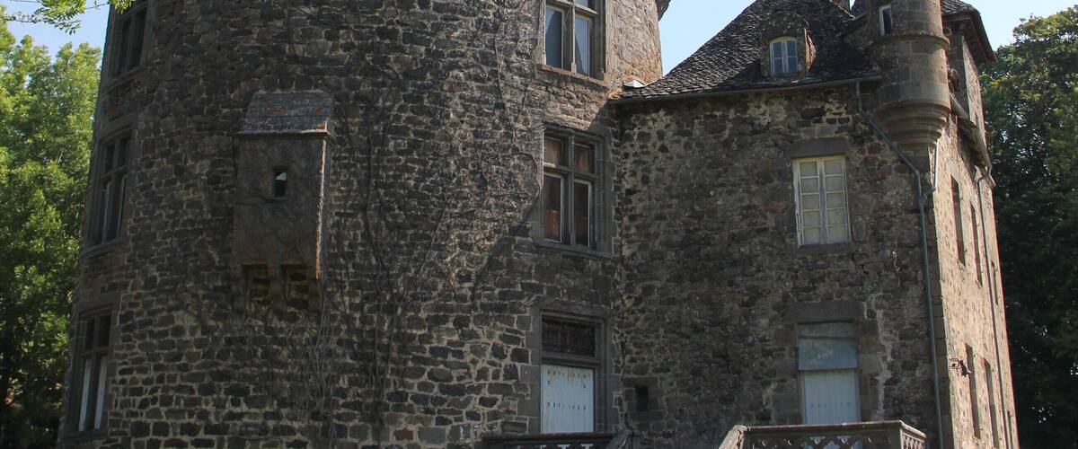 A historic stone castle with a round tower, a turret, and a staircase leading to the entrance.