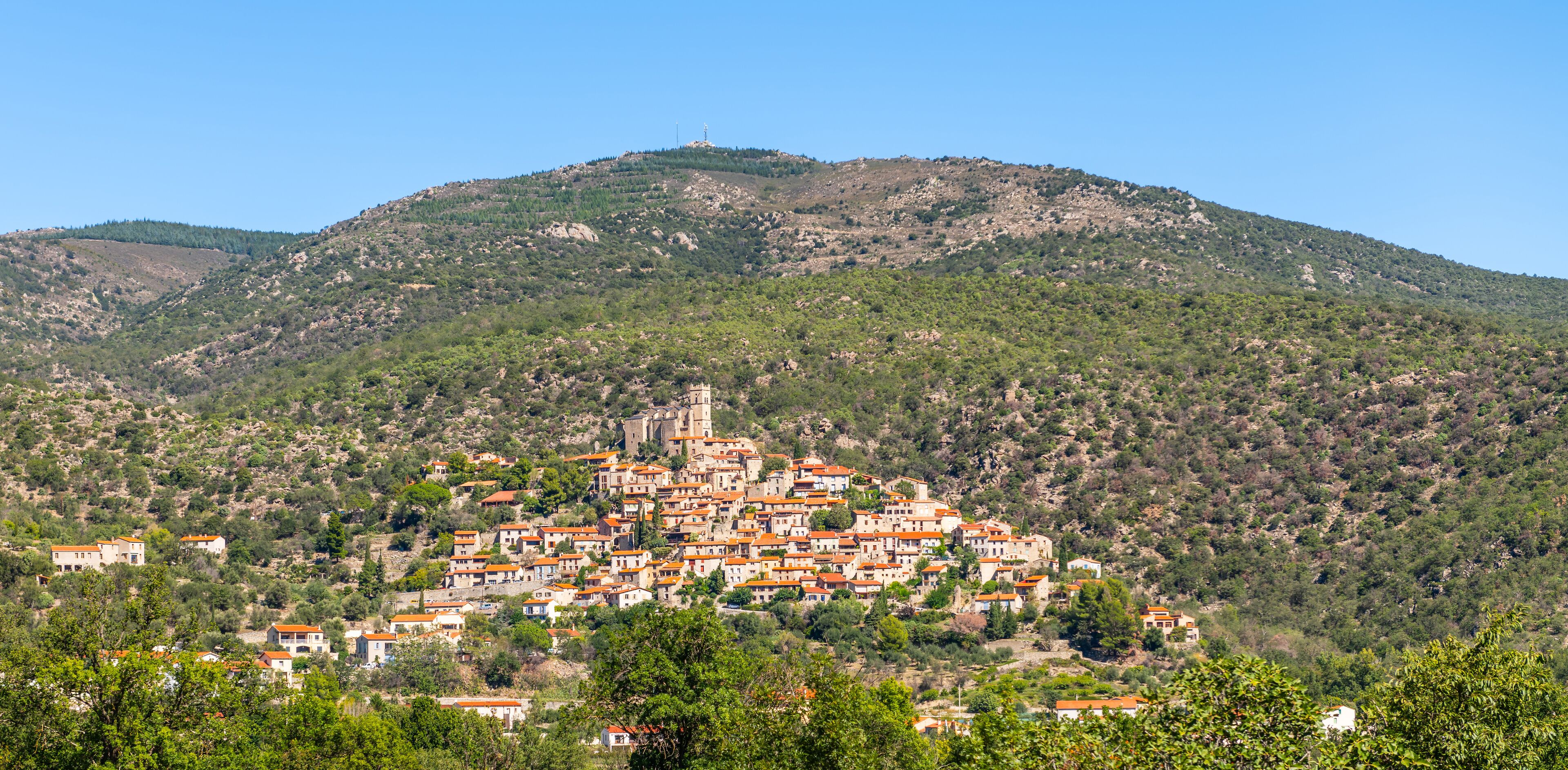 A hillside village with terracotta-roofed buildings and a church on a hilltop.