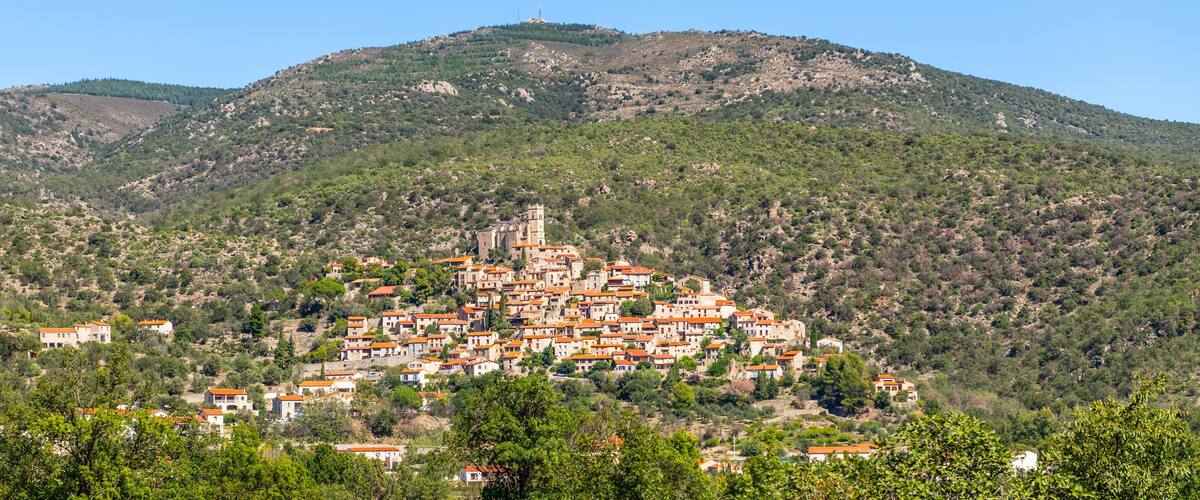 A hillside village with terracotta-roofed buildings and a church on a hilltop.