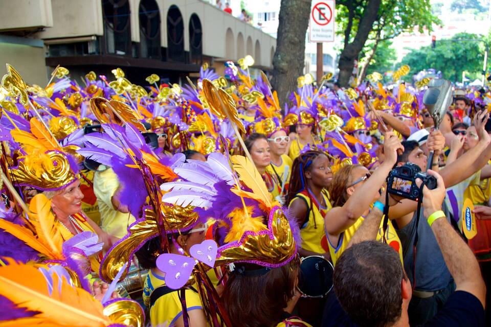 Una multitud de personas vestidas con trajes coloridos adornados con plumas y detalles dorados.
