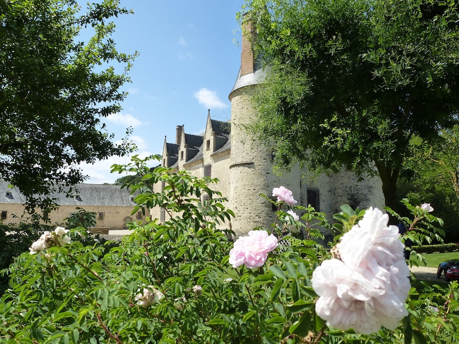 Een historisch gebouw met een ronde toren en een tuin vol bloeiende bloemen.
