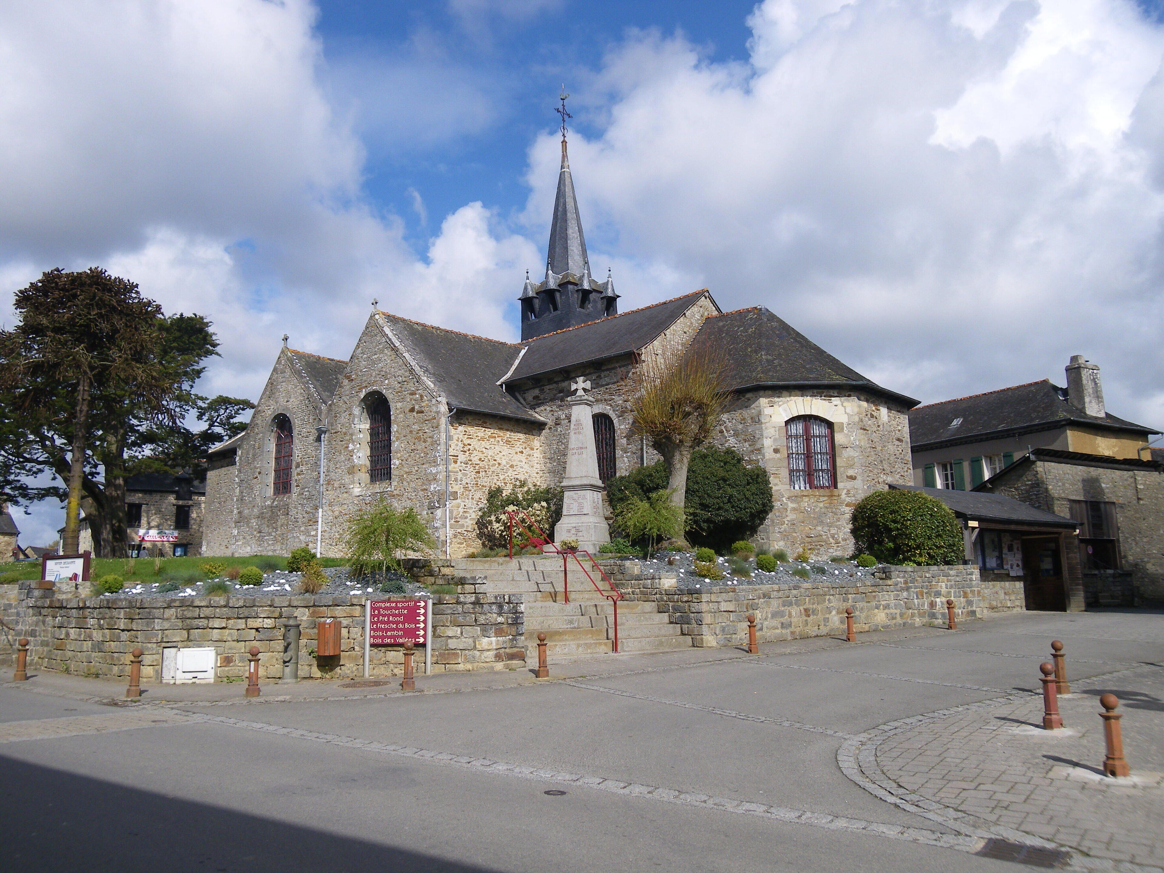 A historic church with a tall steeple, stone walls, and a paved courtyard.