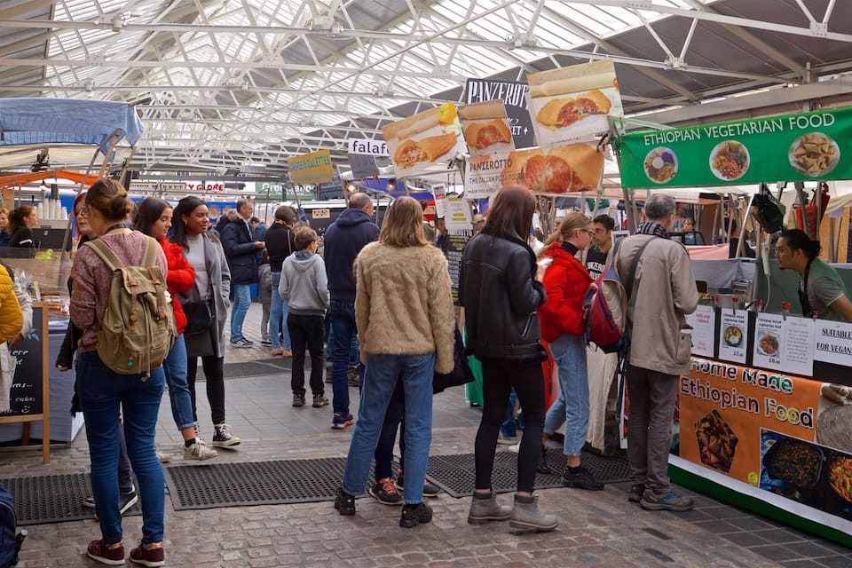 A crowded indoor market with various food stalls, including Ethiopian vegetarian food.