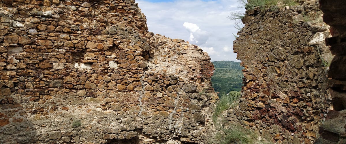 Ancient stone ruins with a mountainous landscape in the background.