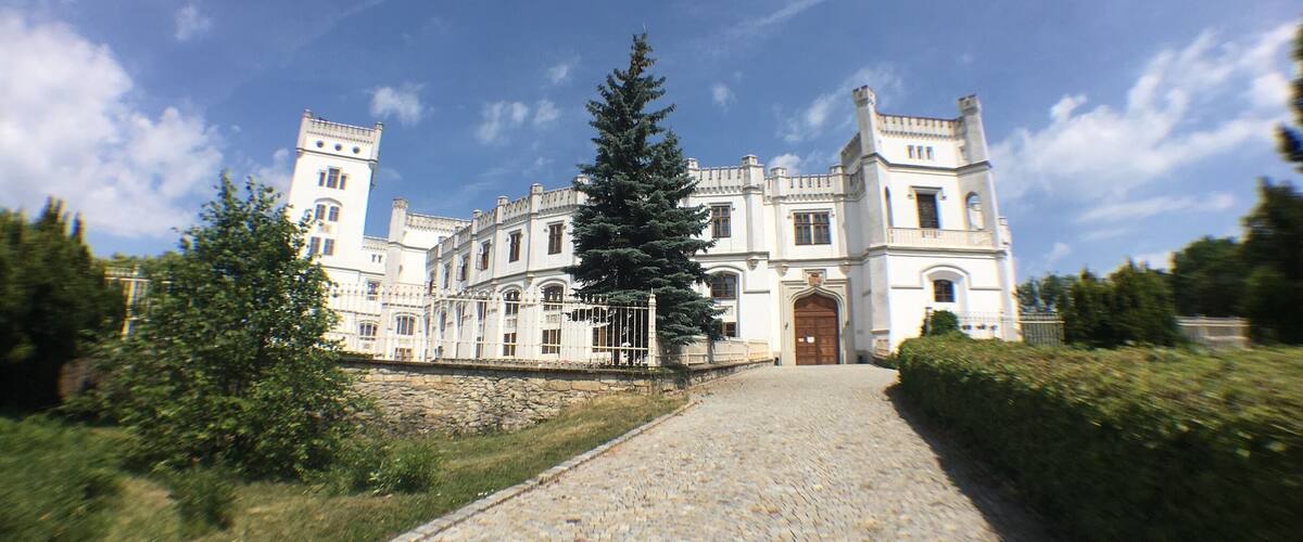 A large, historic building with a cobblestone pathway leading to the entrance.