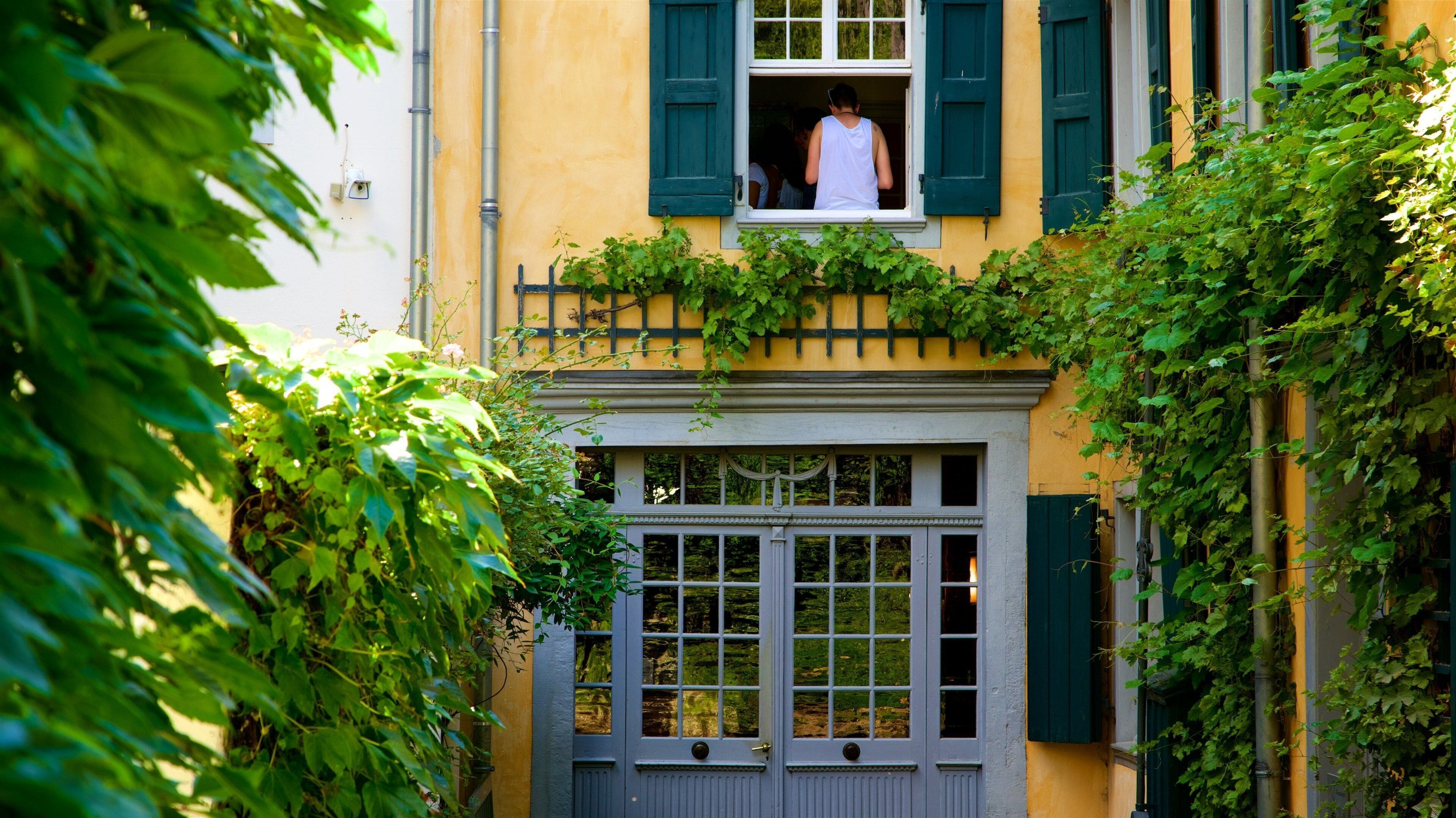 A yellow building with green shutters and a white door.