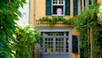 A yellow building with green shutters and a white door.