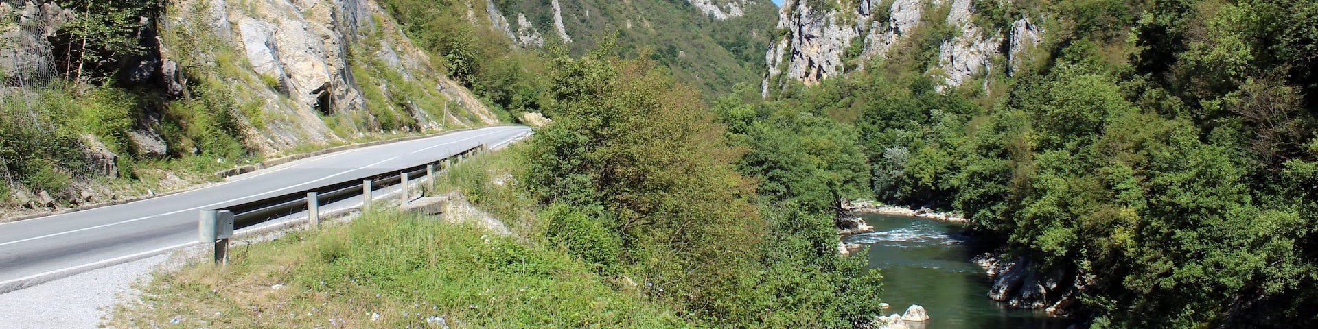 A winding road through a canyon with a river running alongside it.