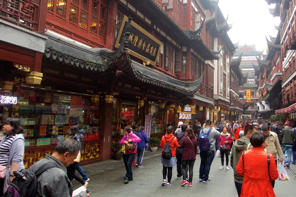 A crowded street lined with traditional red buildings and shops.