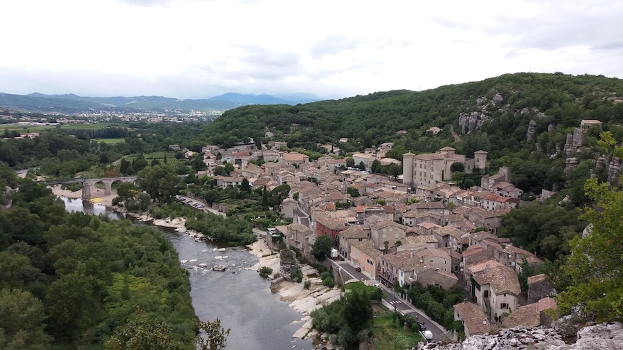 Uma cidade situada num vale, com um rio, rodeada por colinas e uma estrutura semelhante a um castelo.