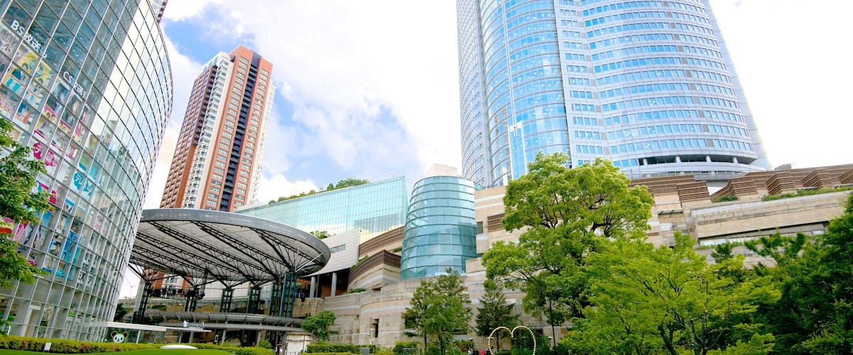 A modern urban park with a pond, lush greenery, and contemporary architecture including high-rise buildings.