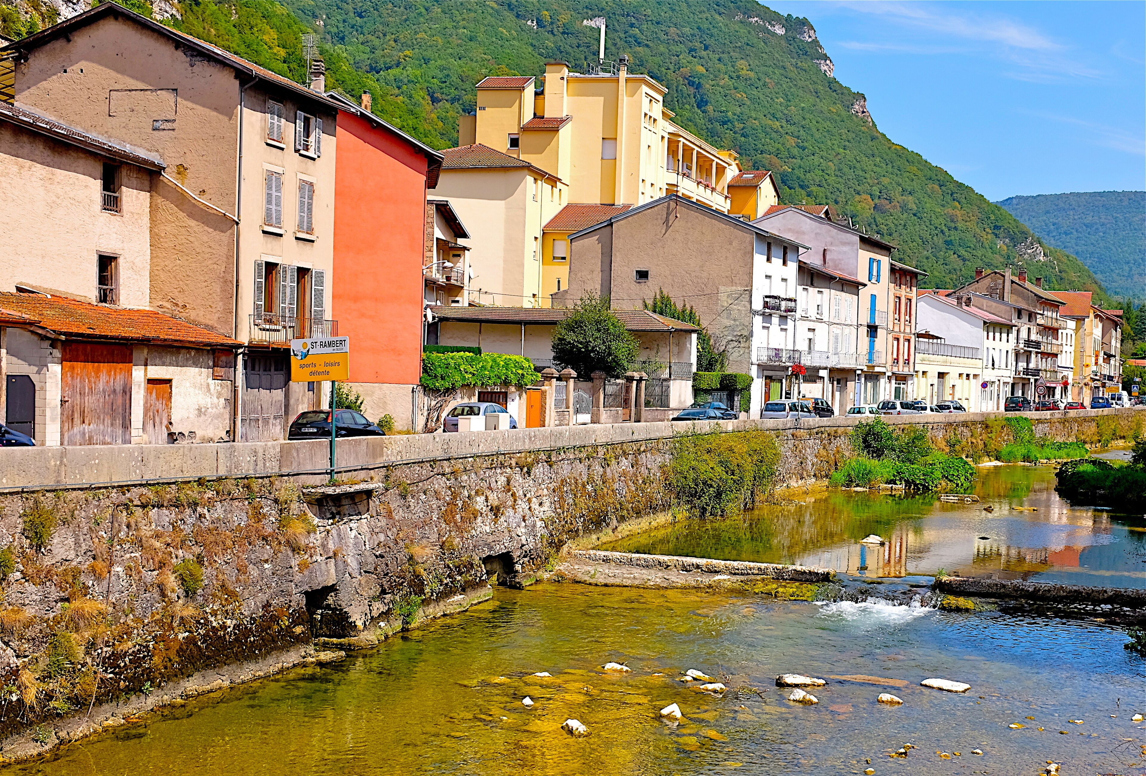 A riverside town with buildings, a bridge, and a mountain in the background.