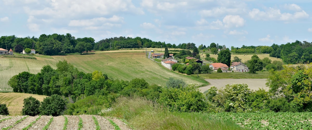 Rolling hills, agricultural fields, and scattered houses in a rural landscape.