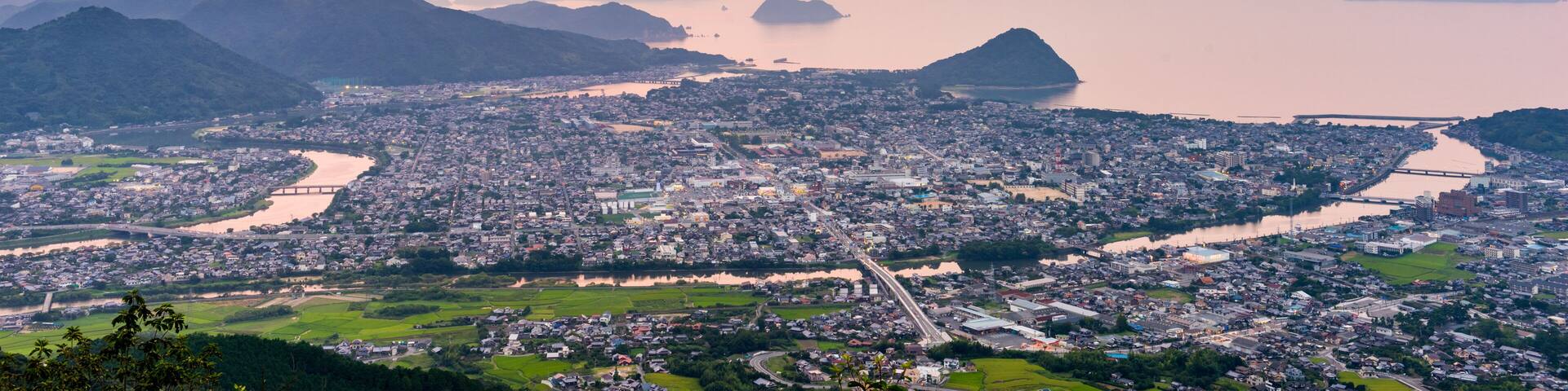 A cityscape with a river, mountains, and a bridge.