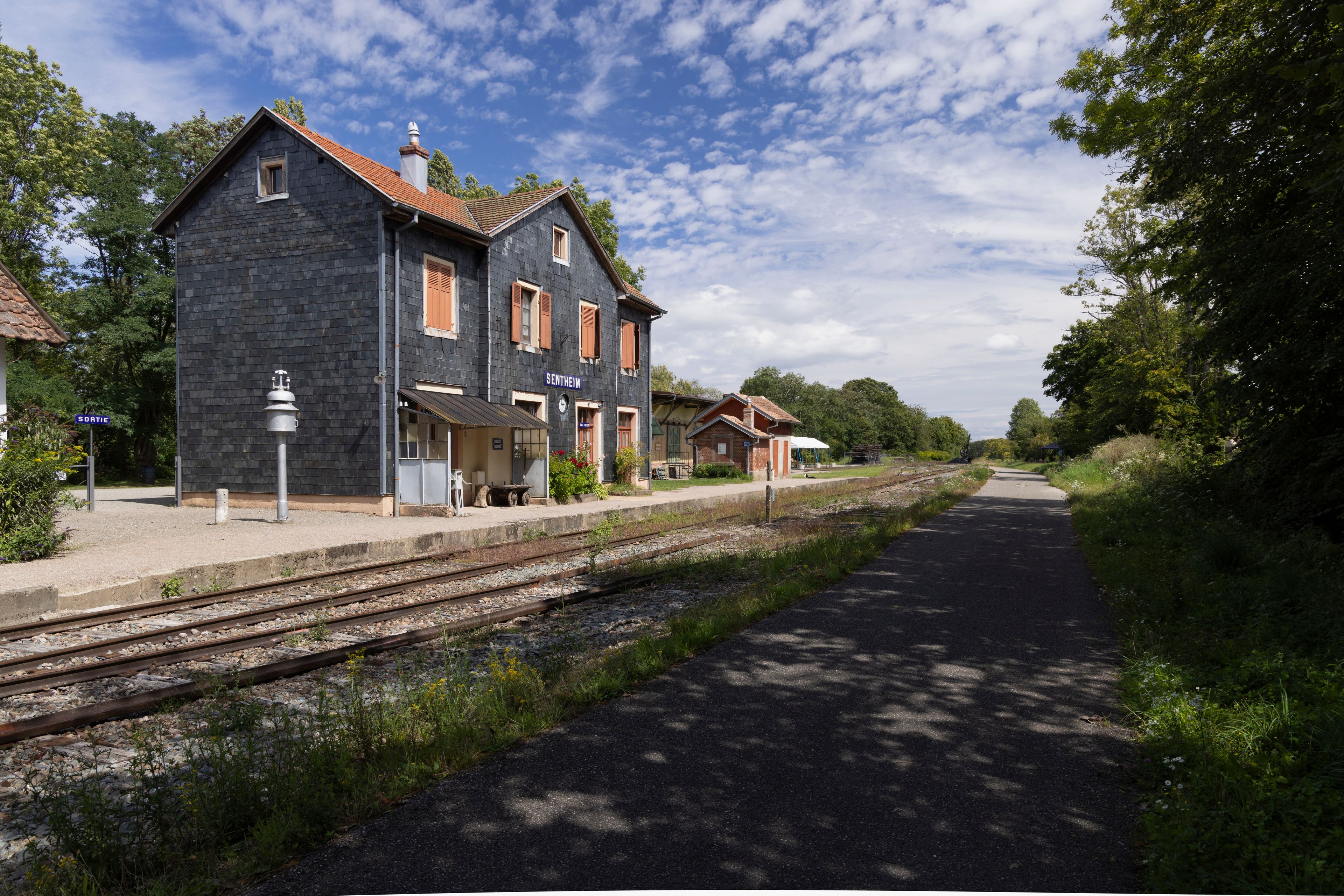 A railway station with a stone building labeled 'SENTHEIM' and a platform.
