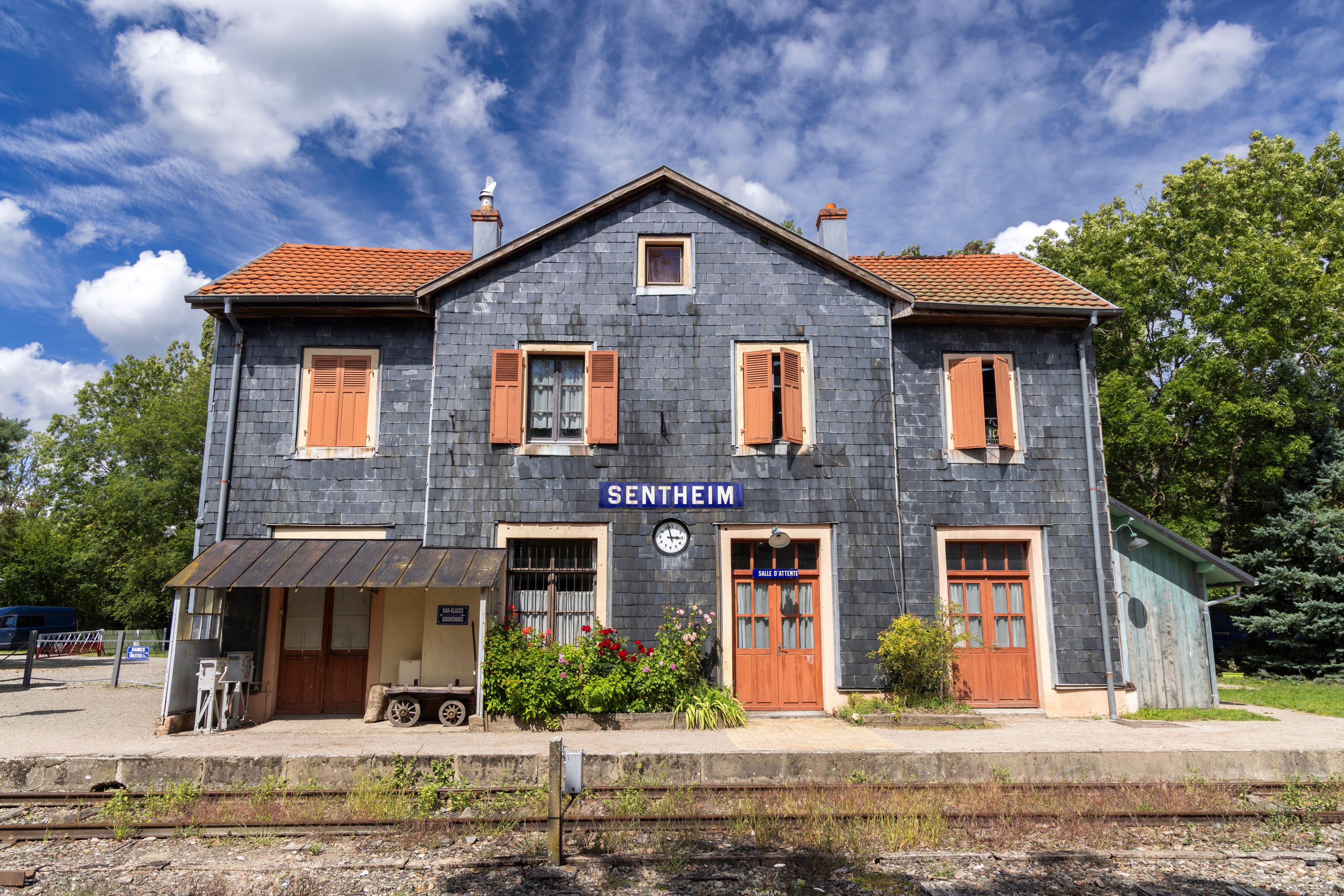 A two-story building with a sign reading 'SENTHEIM' and a clock on the front.