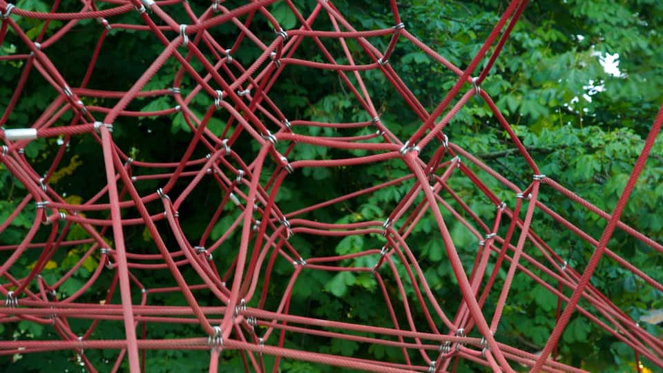 A red rope climbing structure in a garden.