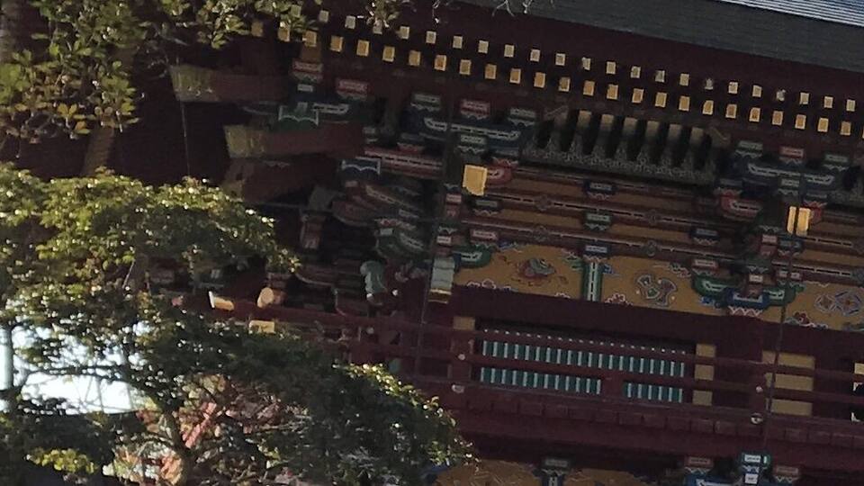 A traditional building with intricate roof decorations and a red structure with yellow accents.