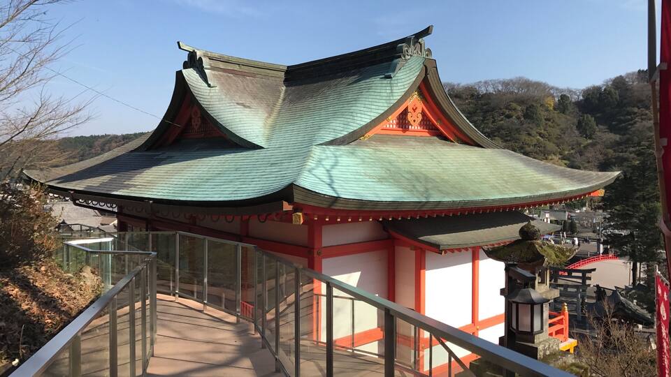 A traditional Japanese temple with a curved roof and red accents.