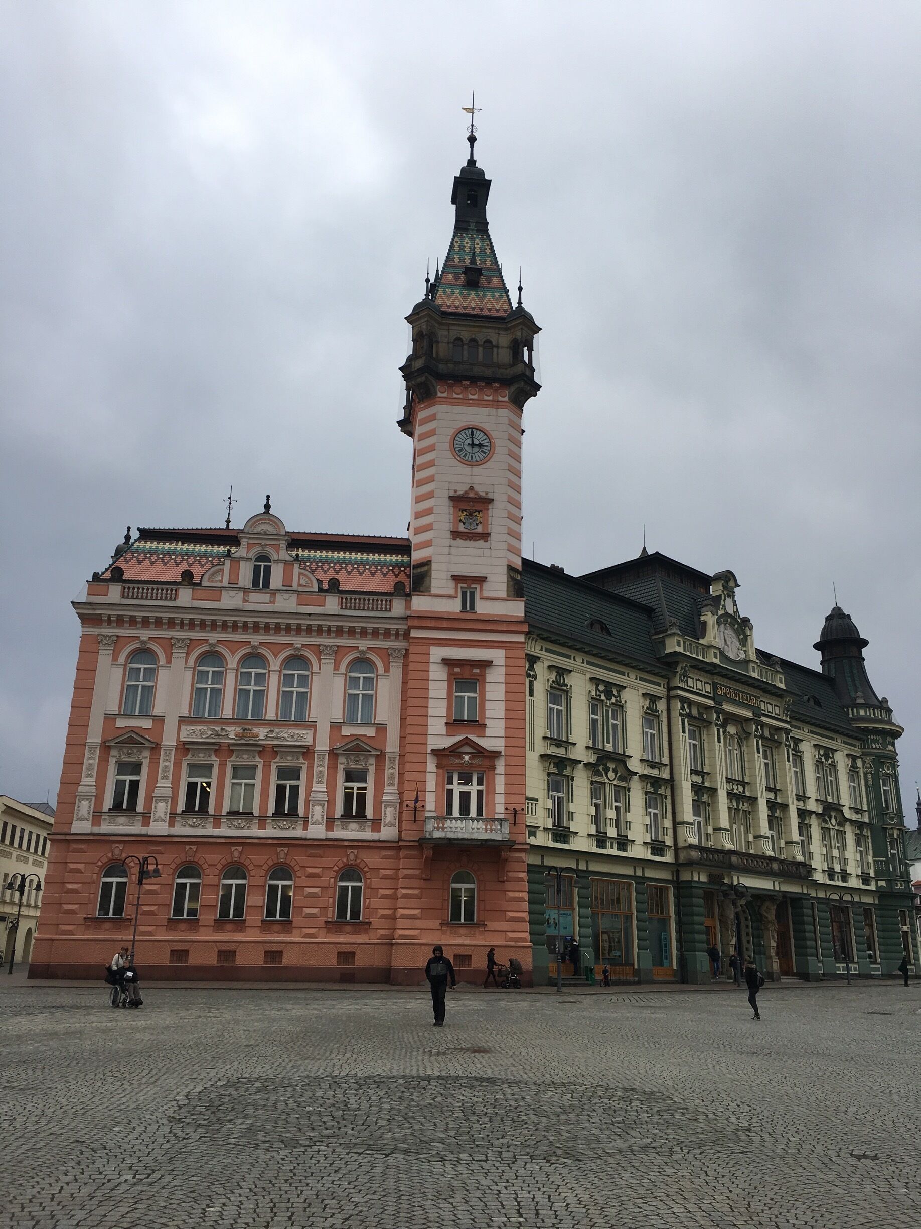 A historic building with a prominent clock tower and a cobblestone plaza.