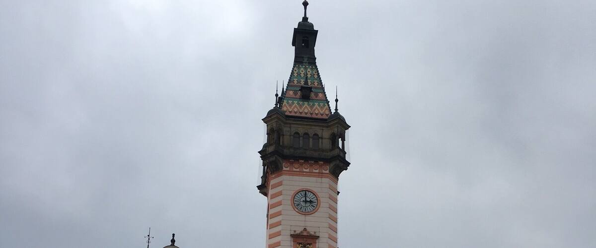 A historic building with a prominent clock tower and a cobblestone plaza.
