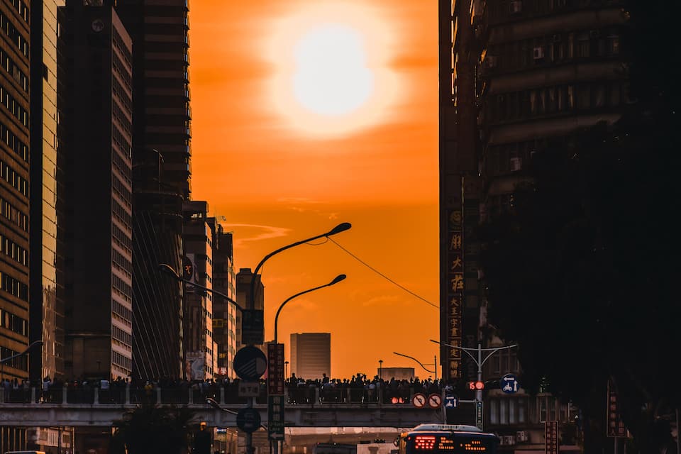 A sunset over a cityscape with tall buildings and a busy street.