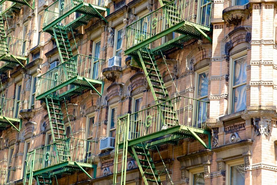 Un edificio con múltiples escaleras de incendios verdes y detalles arquitectónicos ornamentados.