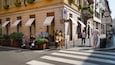 A street with pedestrians, a crosswalk, and storefronts with the name "Cartier".