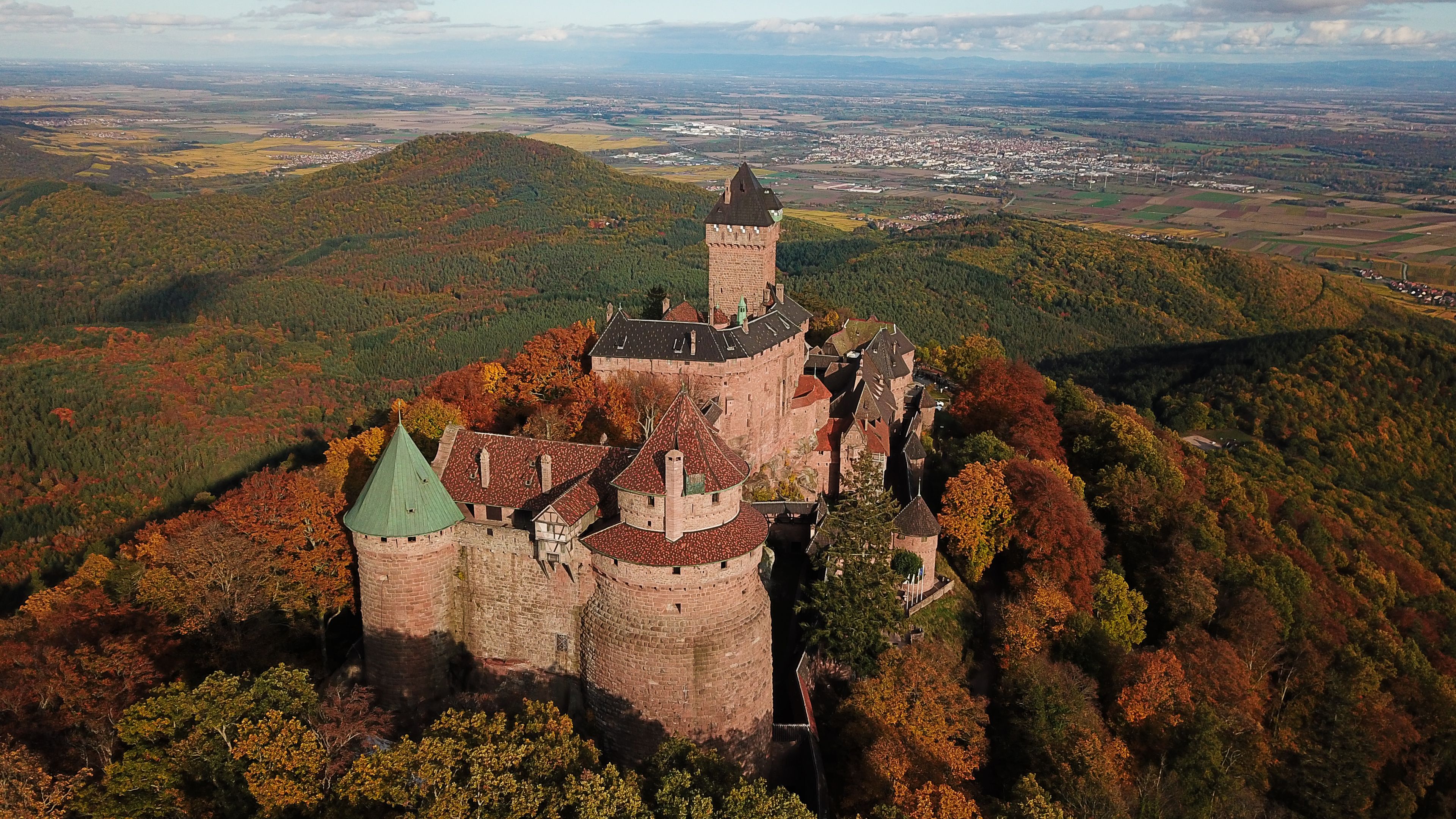 Um castelo rodeado por folhagem outonal numa colina.