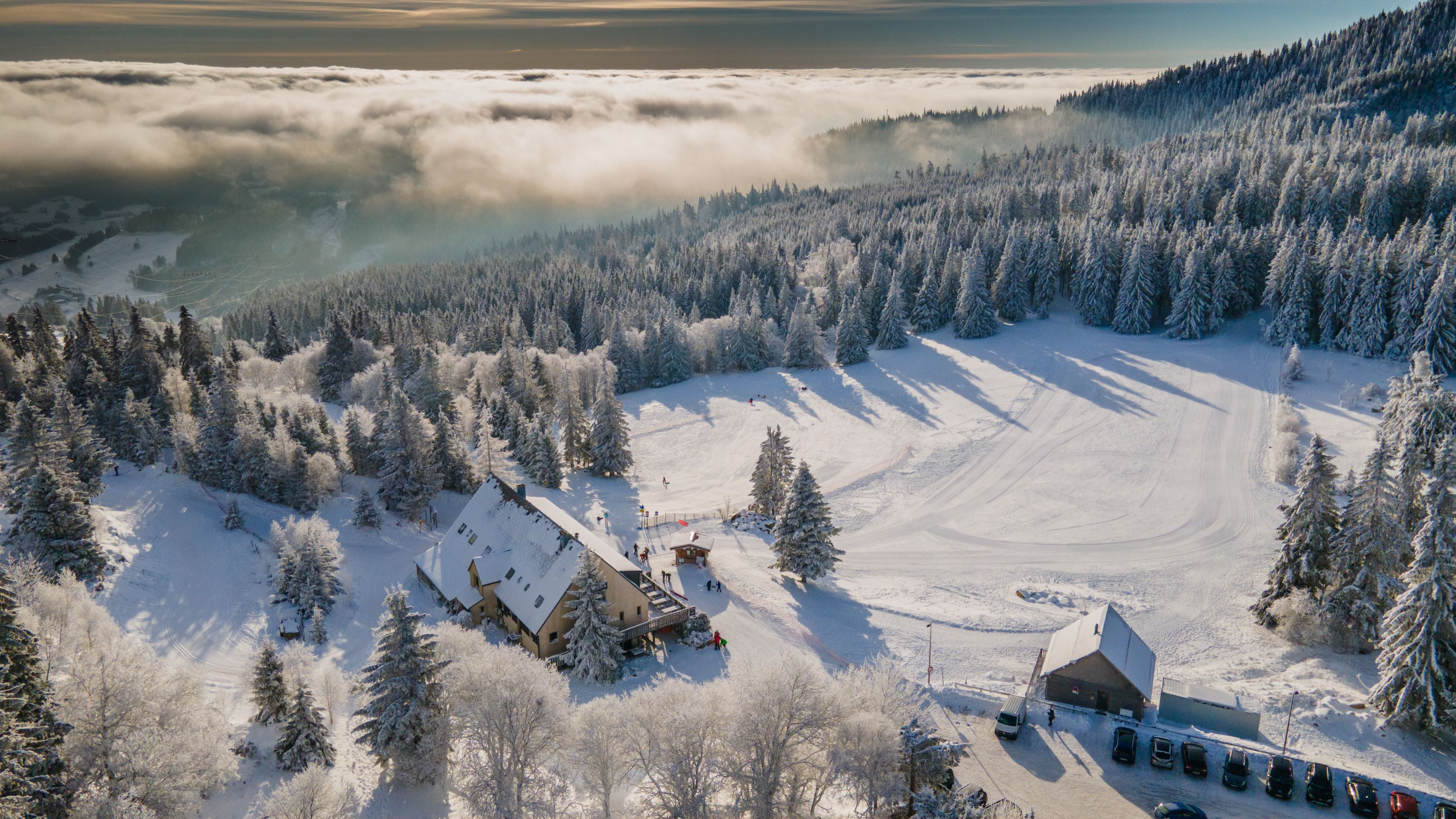 Estância de esqui coberta de neve, com montanhas ao fundo e área arborizada.
