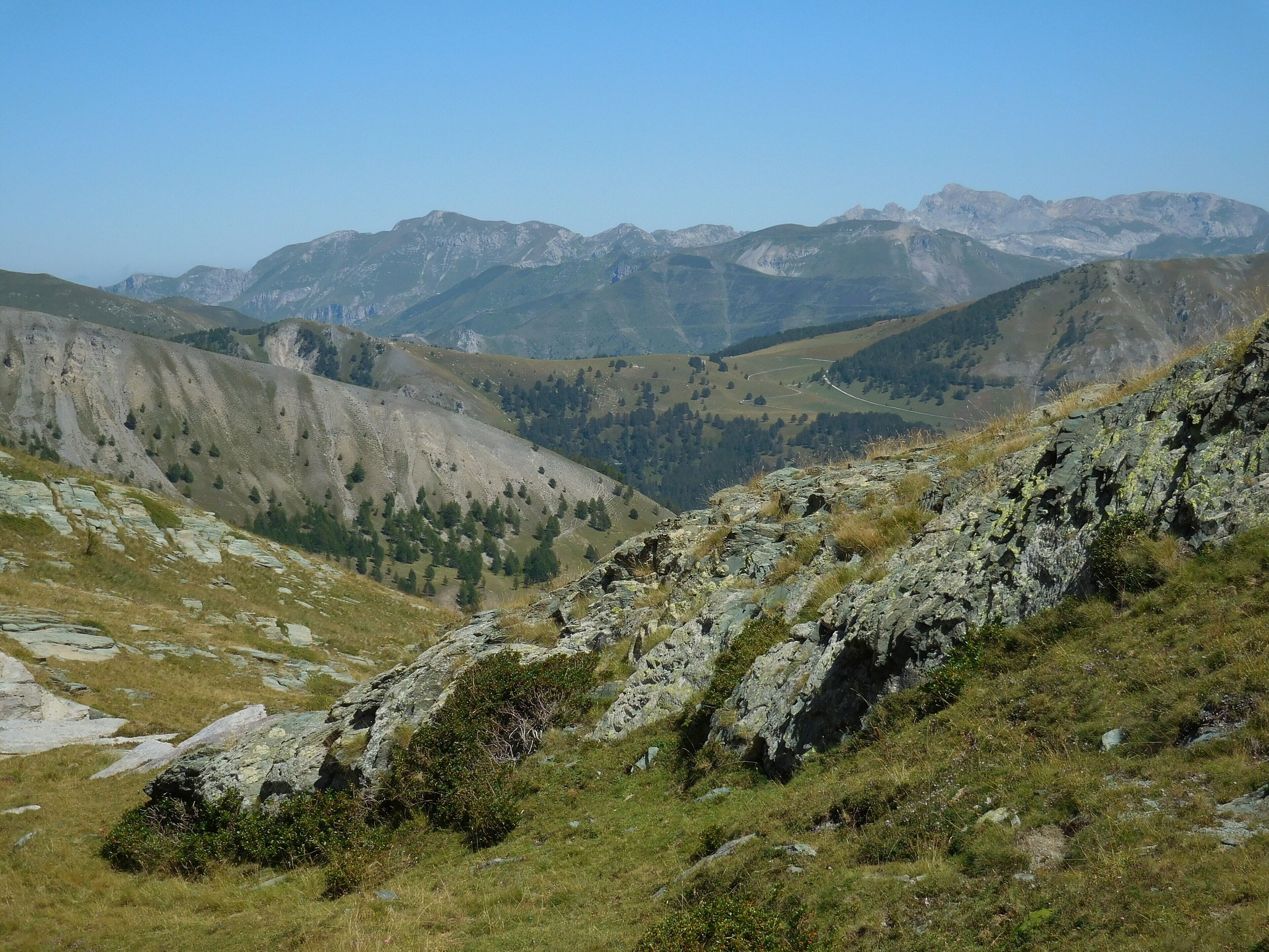 Le vallon de Fontanalba depuis la zone au-dessus des lacs Jumeaux. Derrière la croupe herbeuse de la baisse de Peïrefique entre le vallon de Castérino et la vallée de la Roya, la crête frontière entre la France et l'Italie avec à gauche le col de Tende et à droite la pointe Marguareis.