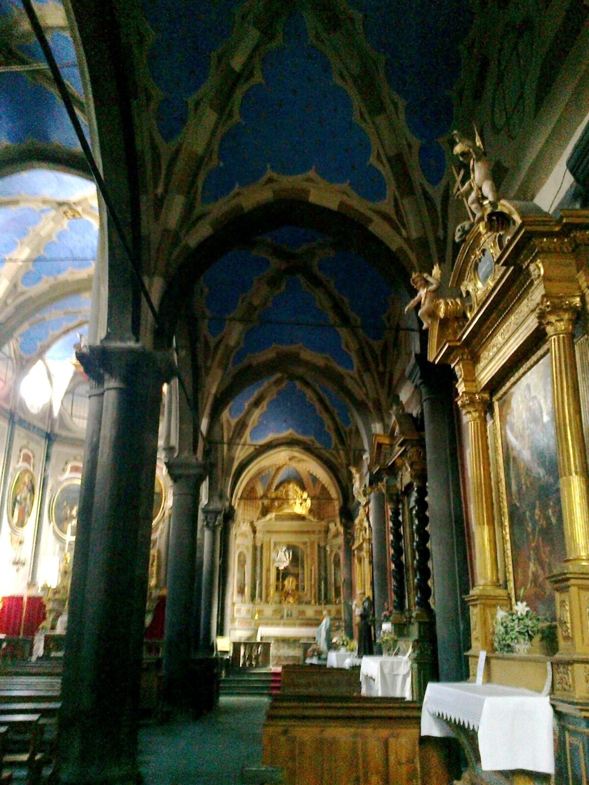 A church interior with Gothic arches, ornate columns, and religious statues.