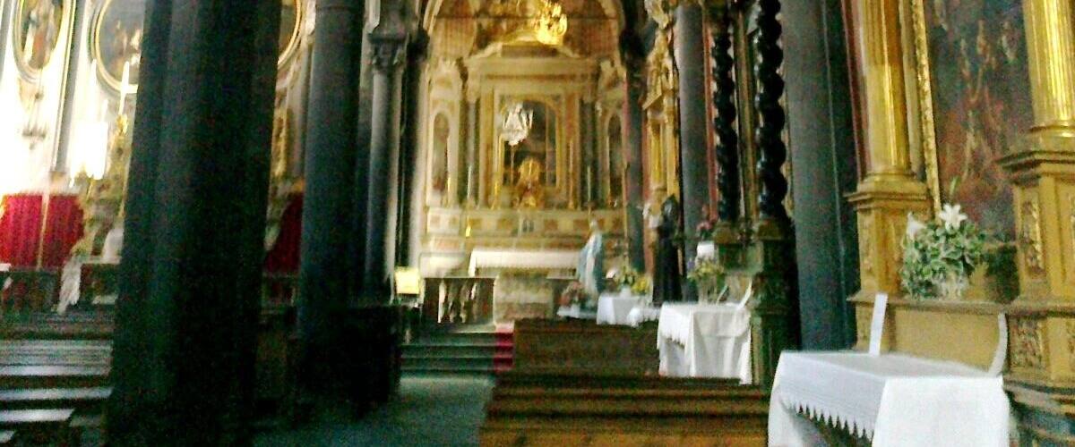 A church interior with Gothic arches, ornate columns, and religious statues.